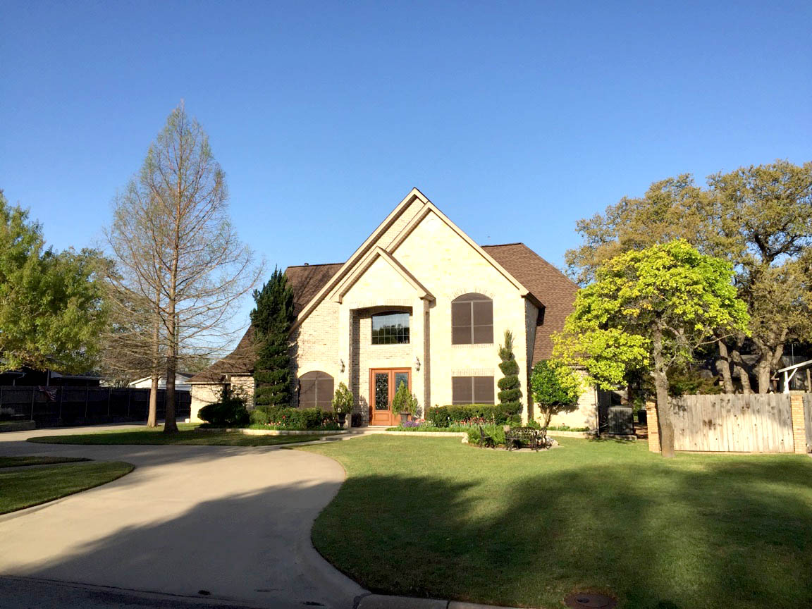 Completed residential roof replacement on two-story brick home in Stephenville TX by Heritage Roofing