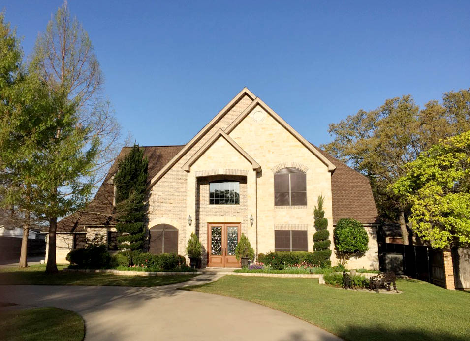 Completed roof replacement on two-story stone home in Central Texas — Heritage Roofing