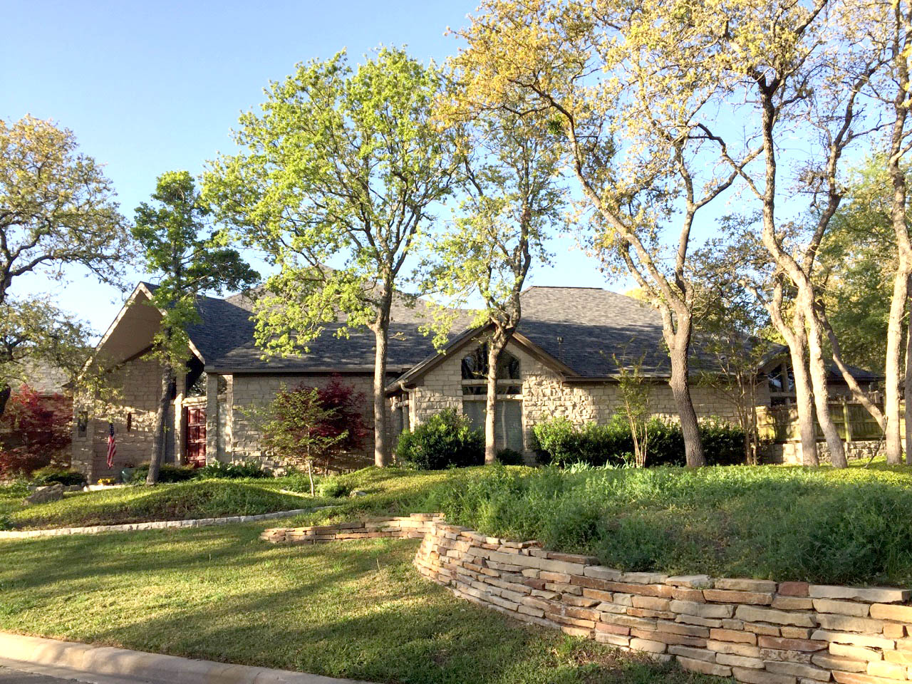 Stone home with new architectural shingle roof installed by Heritage Roofing in Stephenville TX