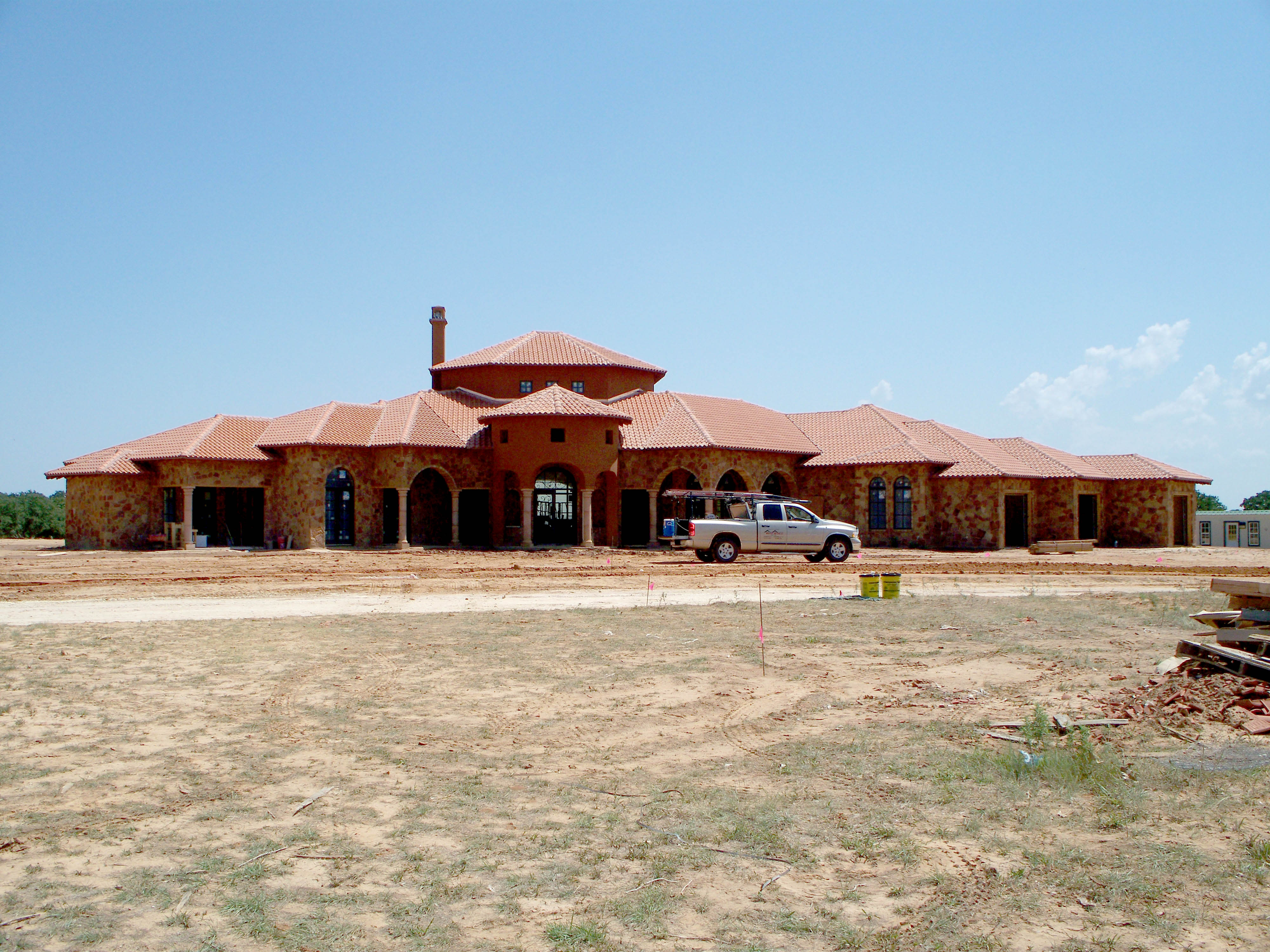Large Spanish Mediterranean mansion with clay tile roof under construction — Heritage Roofing crew on site